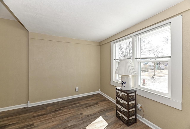 empty room with baseboards, a healthy amount of sunlight, and dark wood finished floors