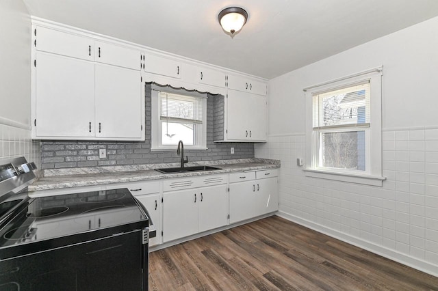 kitchen featuring electric range, dark wood-type flooring, a sink, tile walls, and white cabinets