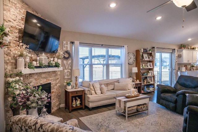 living room with a wealth of natural light, wood finished floors, a fireplace, and vaulted ceiling