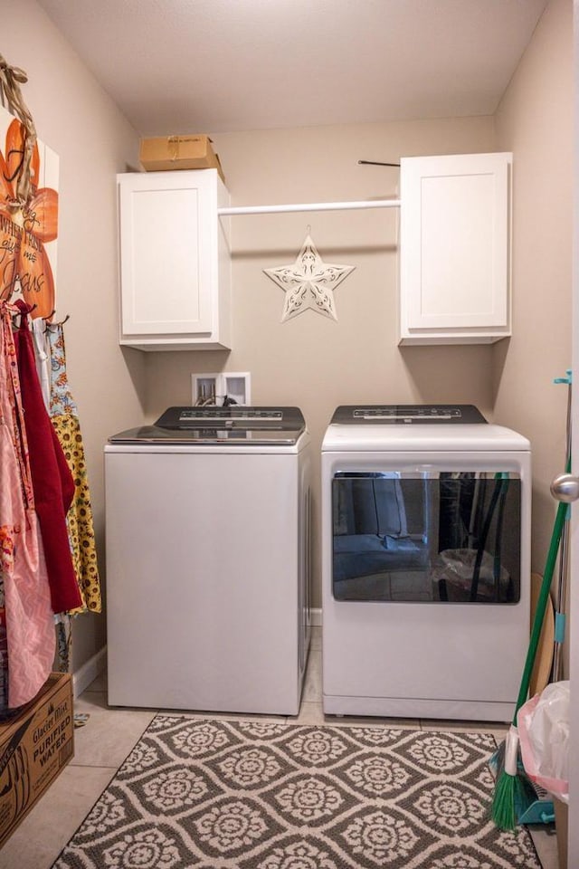 laundry area featuring light tile patterned floors, cabinet space, and independent washer and dryer