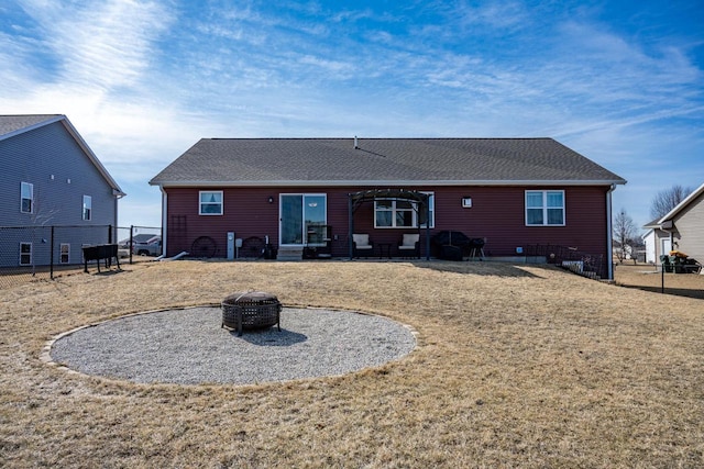 back of house featuring fence, a lawn, roof with shingles, and an outdoor fire pit