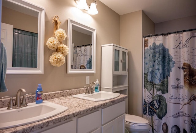 bathroom featuring double vanity, toilet, and a sink