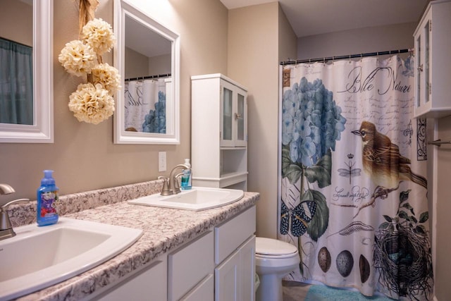 full bath with double vanity, toilet, and a sink