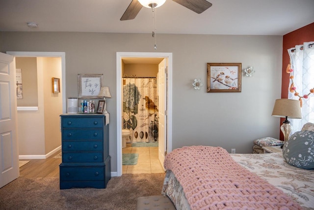 carpeted bedroom featuring baseboards, ensuite bathroom, and ceiling fan