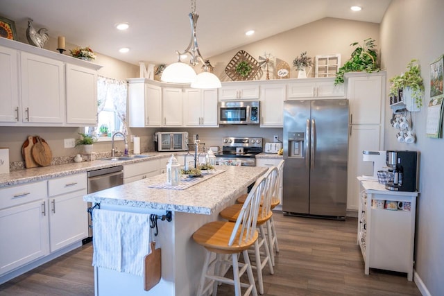 kitchen with a sink, a center island, stainless steel appliances, white cabinets, and vaulted ceiling