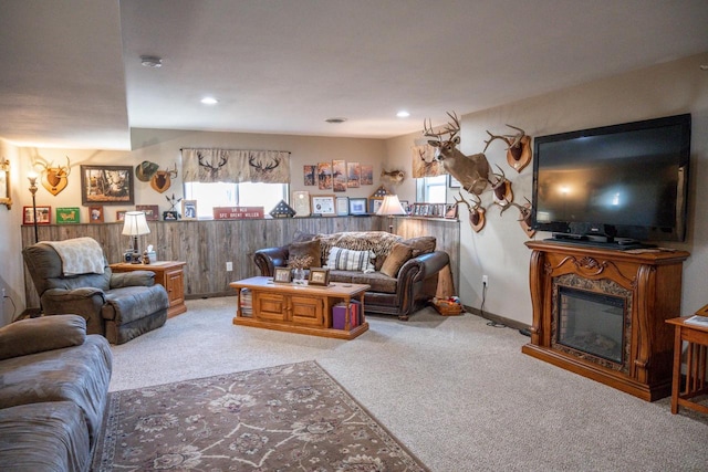 living room featuring a glass covered fireplace, recessed lighting, wooden walls, and carpet floors