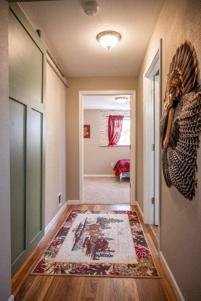 corridor with wood finished floors, visible vents, and baseboards