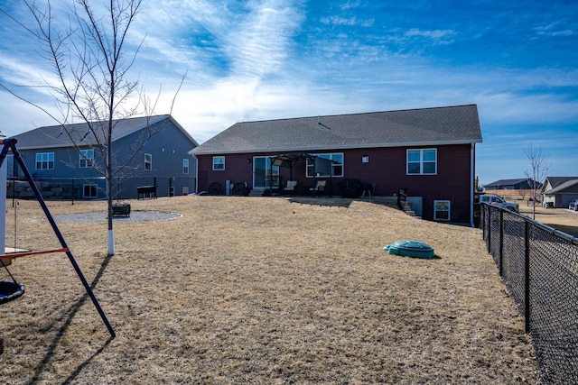 back of house with a fenced backyard and a shingled roof