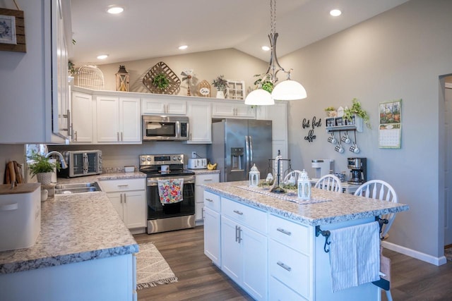 kitchen featuring a kitchen island, dark wood-type flooring, white cabinets, vaulted ceiling, and appliances with stainless steel finishes