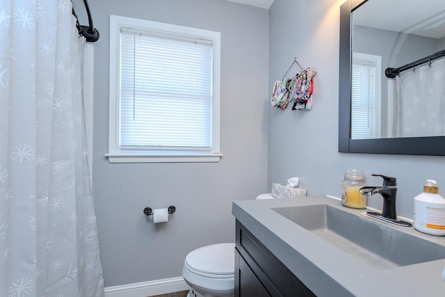 bathroom with toilet, vanity, and baseboards