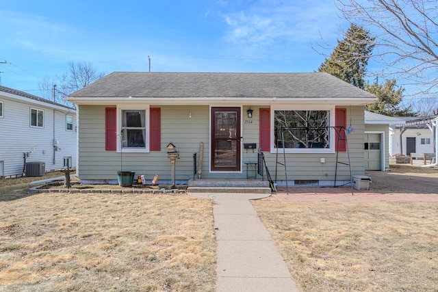 bungalow-style house with a front yard, an attached garage, and roof with shingles