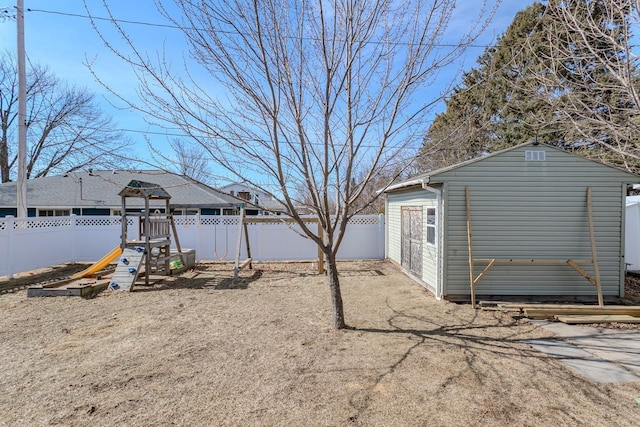 view of yard featuring an outdoor structure, a fenced backyard, and a playground