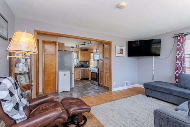 living area featuring visible vents, a healthy amount of sunlight, baseboards, and wood finished floors