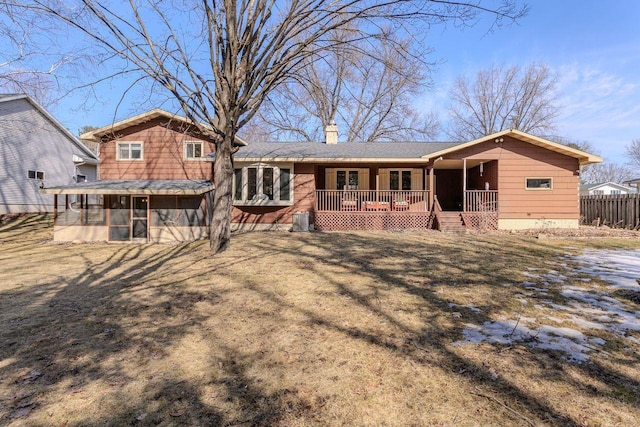 back of house featuring a porch, a chimney, fence, and a sunroom