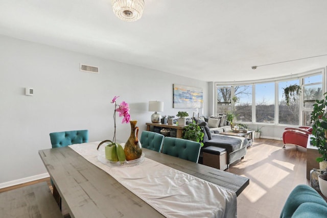 dining space featuring visible vents, baseboards, and wood finished floors