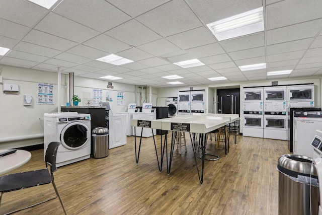 kitchen with stacked washing maching and dryer, a paneled ceiling, wood finished floors, and washing machine and clothes dryer