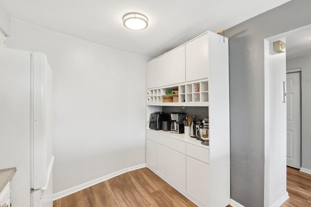 kitchen featuring open shelves, light countertops, light wood-type flooring, and freestanding refrigerator