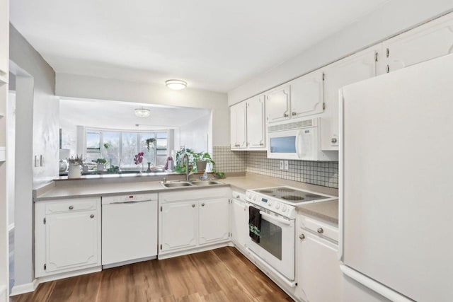 kitchen featuring white cabinetry, white appliances, and a sink