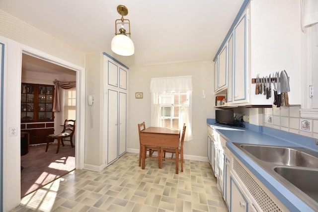 kitchen with pendant lighting, light countertops, baseboards, and a sink