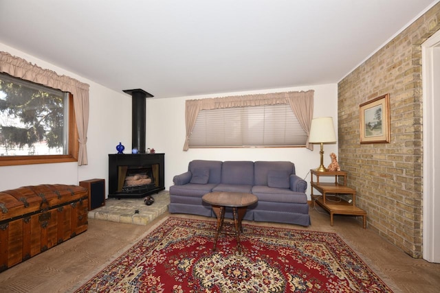 living area with a wood stove, wood finished floors, and brick wall