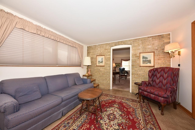 living area with baseboards, arched walkways, and brick wall