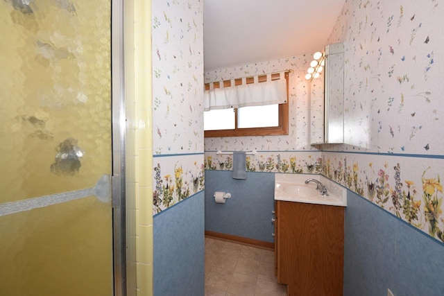 full bath with baseboards, a stall shower, vanity, and wallpapered walls