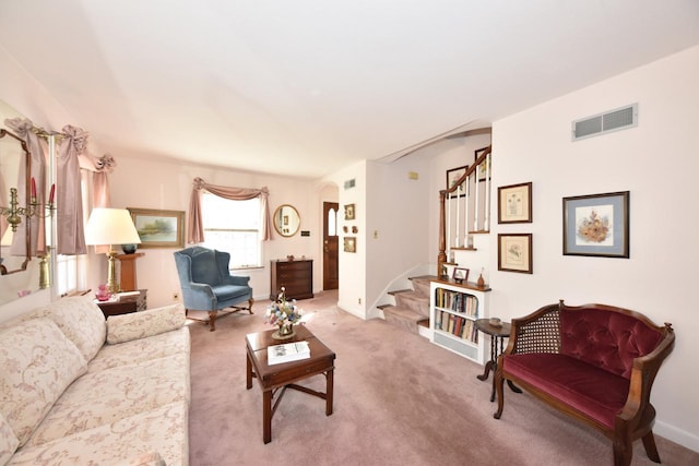 carpeted living room featuring arched walkways, visible vents, stairway, and baseboards