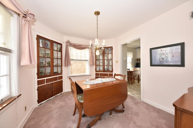 carpeted dining space featuring visible vents, baseboards, and a chandelier