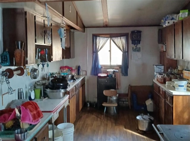 kitchen with light countertops, wood finished floors, brown cabinets, and lofted ceiling