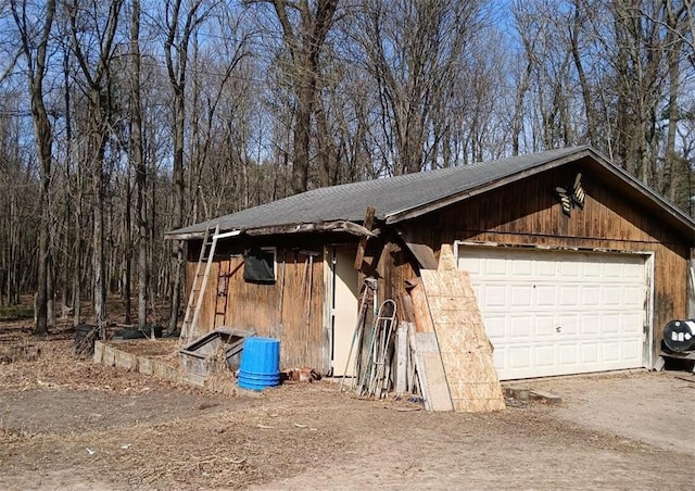 exterior space featuring an outdoor structure, a garage, and dirt driveway