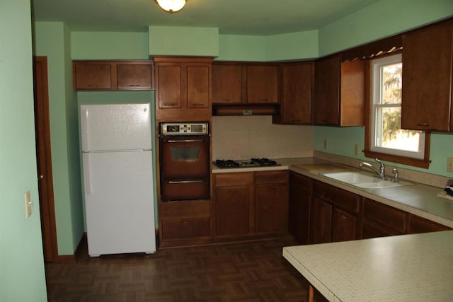 kitchen featuring freestanding refrigerator, a sink, wall oven, under cabinet range hood, and a warming drawer