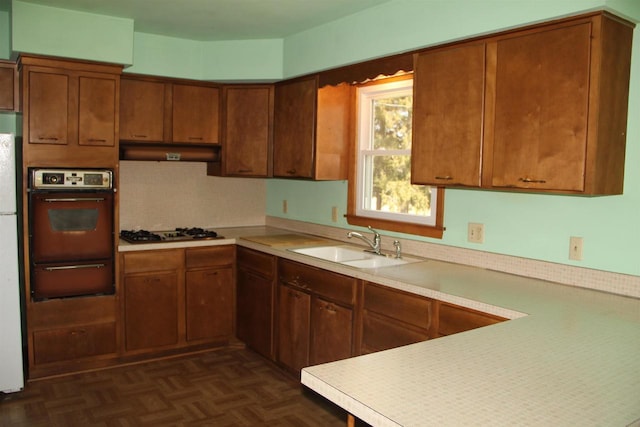 kitchen with a warming drawer, a sink, under cabinet range hood, gas cooktop, and wall oven