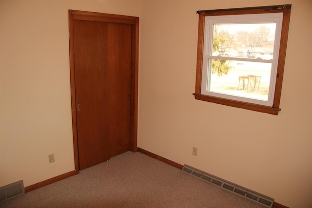 unfurnished room featuring baseboards, visible vents, and light carpet