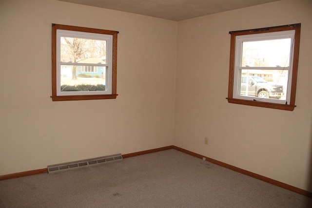 carpeted spare room with visible vents, plenty of natural light, and baseboards