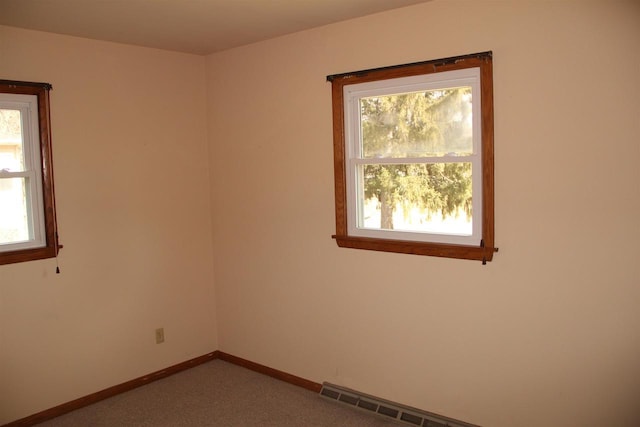 carpeted spare room featuring a baseboard heating unit, a healthy amount of sunlight, and baseboards