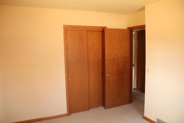 unfurnished bedroom with light colored carpet, baseboards, and a closet