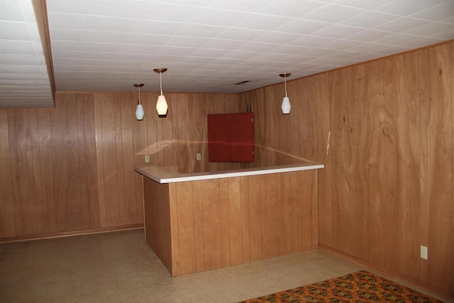 bar featuring decorative light fixtures, wooden walls, and indoor bar