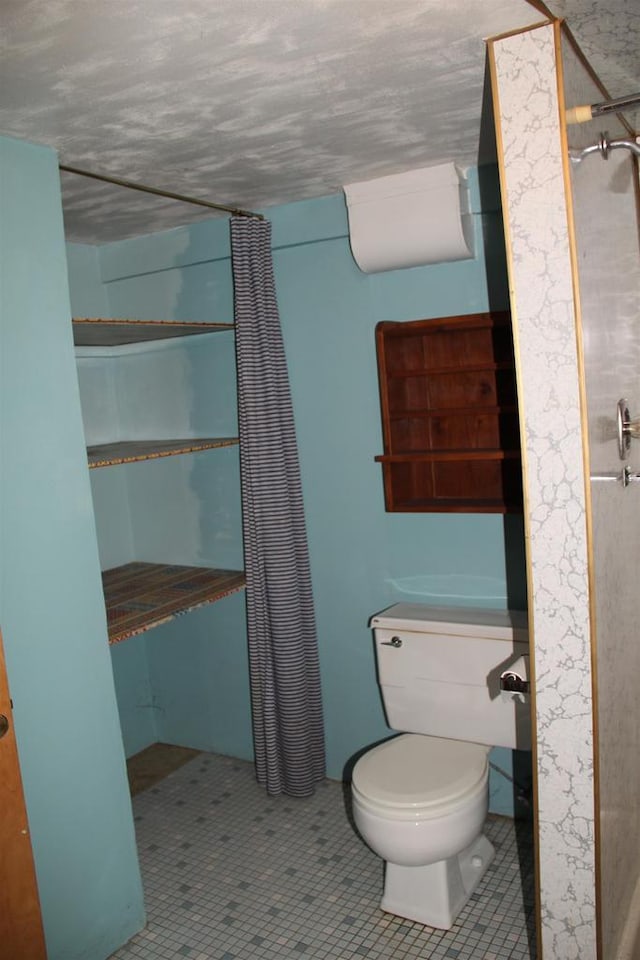 bathroom with a shower with shower curtain, tile patterned floors, and toilet