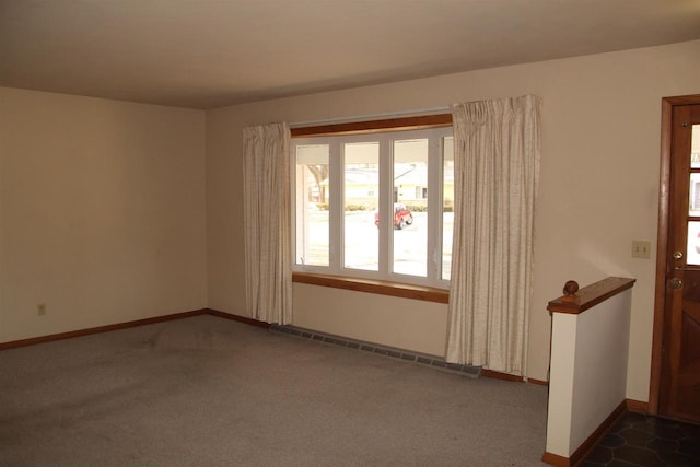 empty room with dark colored carpet, a baseboard radiator, and baseboards