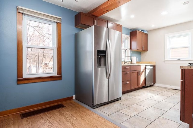 kitchen with brown cabinetry, baseboards, visible vents, and stainless steel appliances