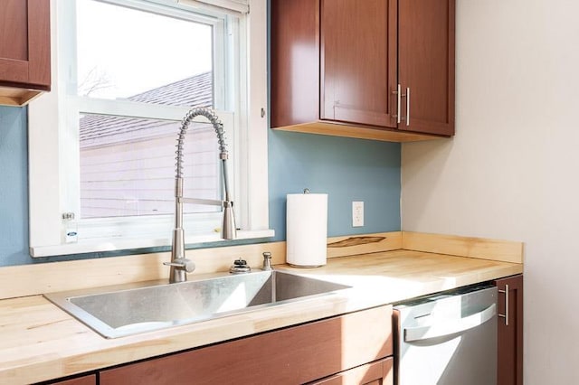 kitchen featuring a sink, dishwashing machine, brown cabinets, and butcher block counters