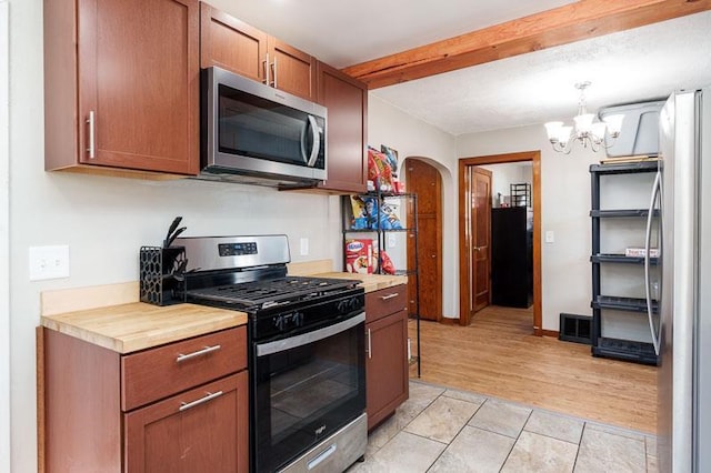 kitchen featuring a chandelier, arched walkways, stainless steel appliances, and light countertops