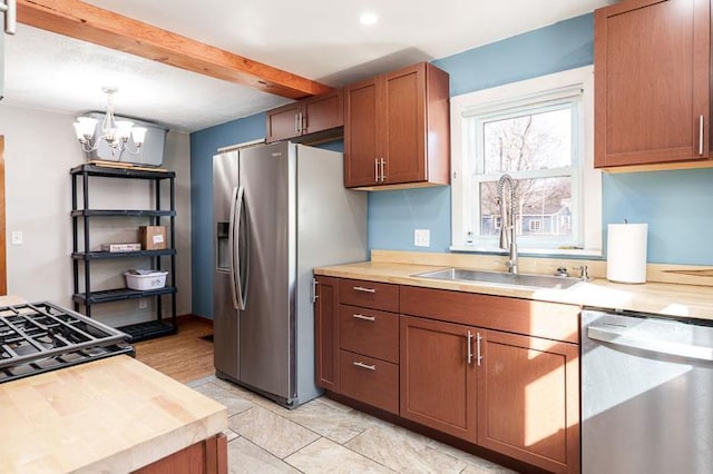 kitchen featuring beamed ceiling, pendant lighting, a notable chandelier, stainless steel appliances, and a sink