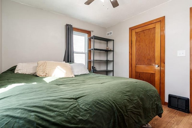 bedroom with a ceiling fan, wood finished floors, and visible vents