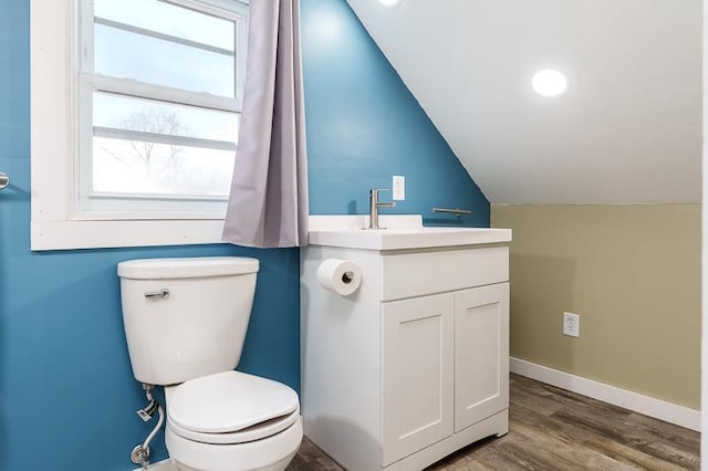 bathroom with baseboards, toilet, lofted ceiling, wood finished floors, and vanity