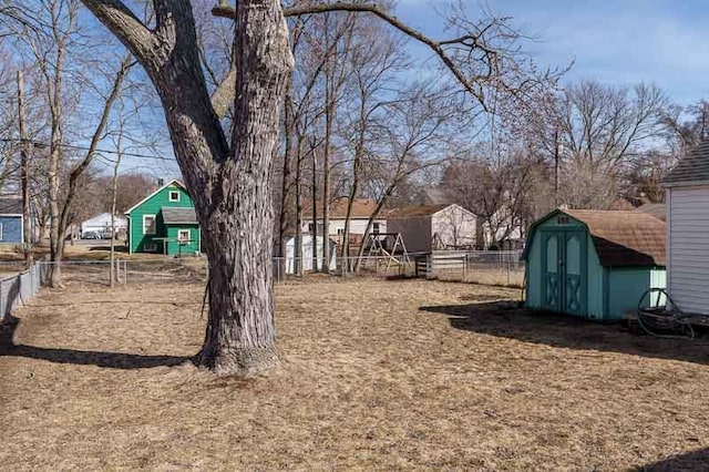 view of yard with a storage shed, fence, and an outbuilding