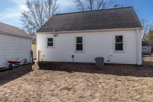 back of house featuring cooling unit and a shingled roof