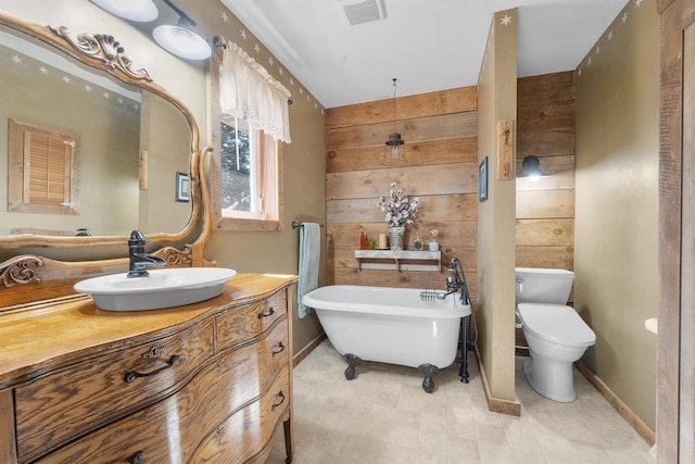 bathroom with vanity, visible vents, a freestanding bath, wood walls, and toilet