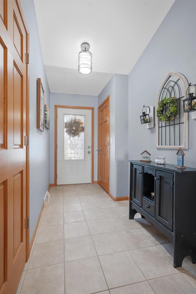 foyer entrance featuring light tile patterned flooring, visible vents, and baseboards