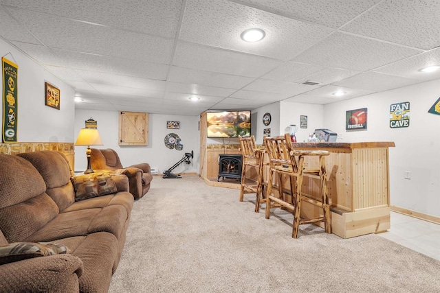 carpeted living room with visible vents, baseboards, a lit fireplace, a bar, and a paneled ceiling